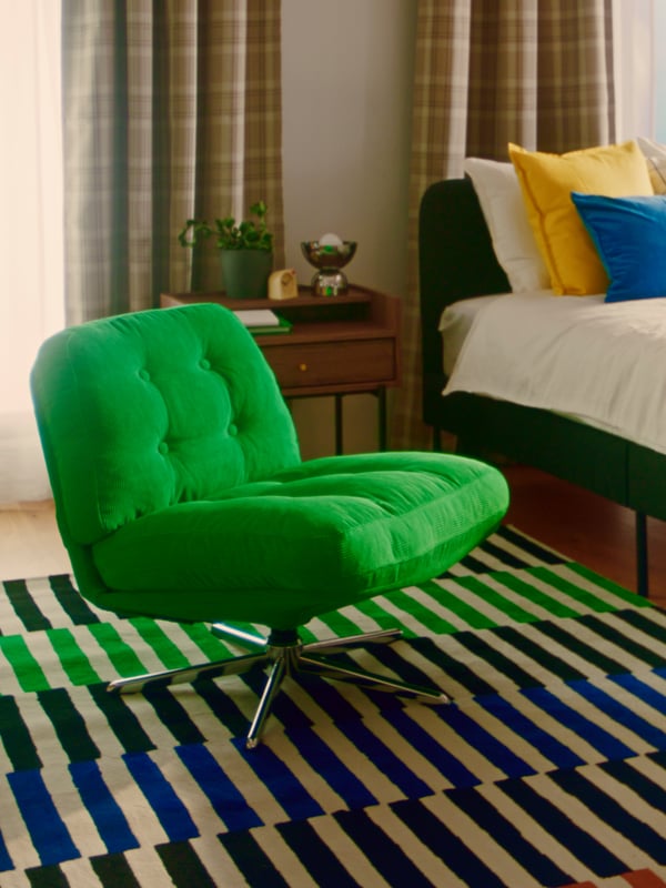 部屋の中央には、カラフルなストライプ柄のカーペットの上に緑色のDYVLINGEチェアが置かれている。