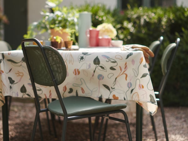 Una mesa de terraza SEGERÖN con un mantel floreado encima