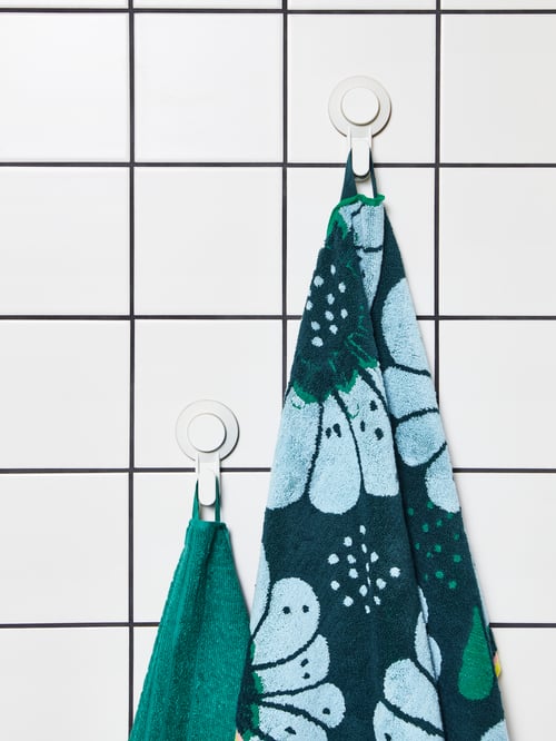 Un lot de deux crochets à ventouse TISKEN fixé sur un mur carrelé blanc. Une serviette verte y est suspendue.