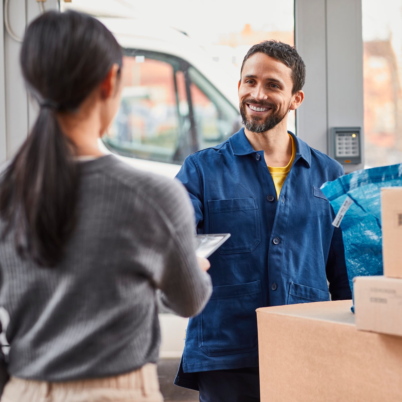A person receiving their delivery from a smiling delivery driver