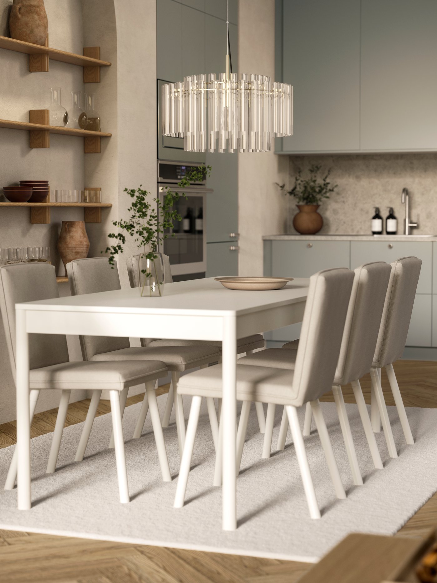 An off-white TONSTAD table with six chairs is on a rug and below a glass chandelier, by an open kitchen with modern fronts.
