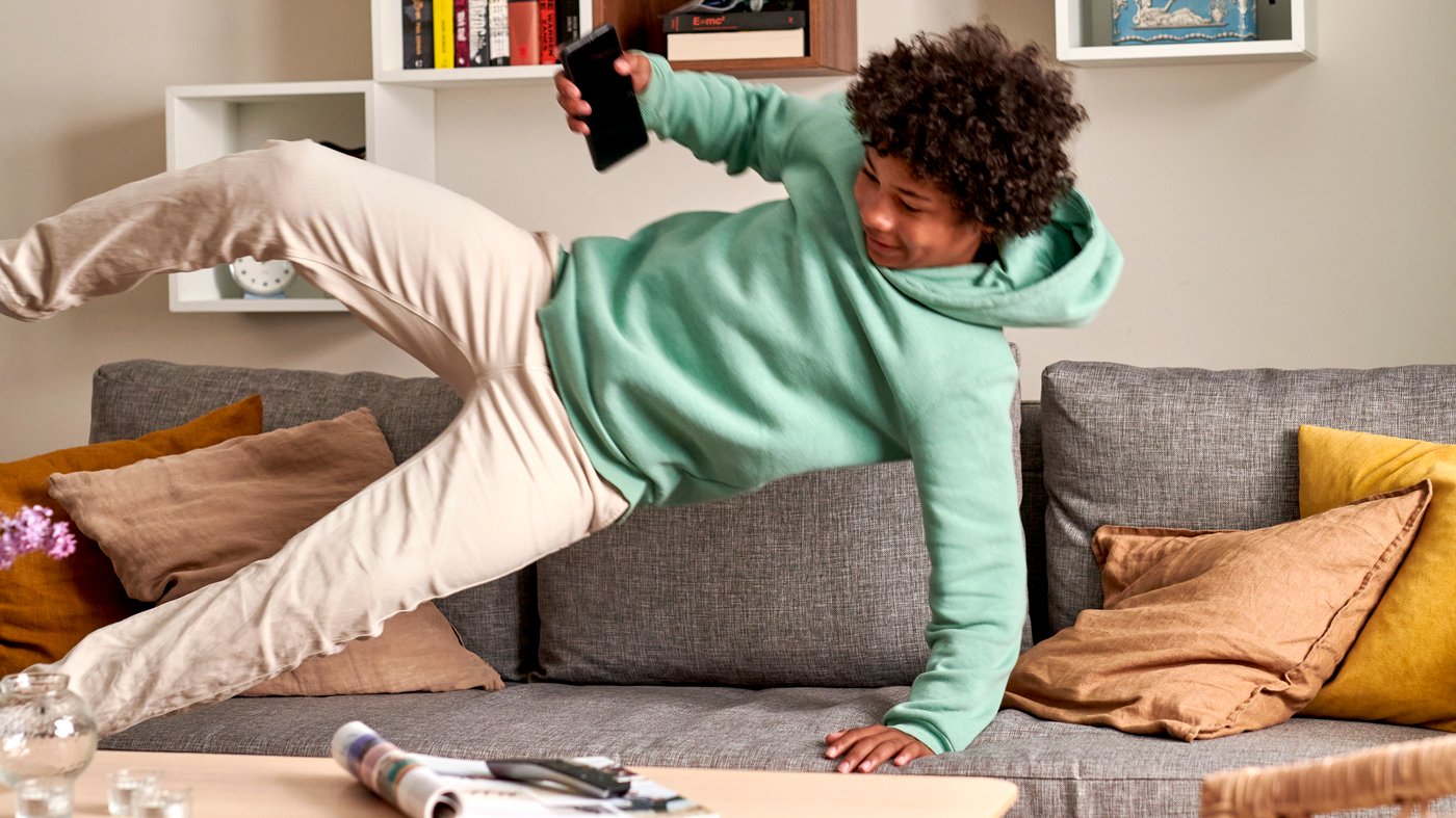 A child jumping into a grey sofa.