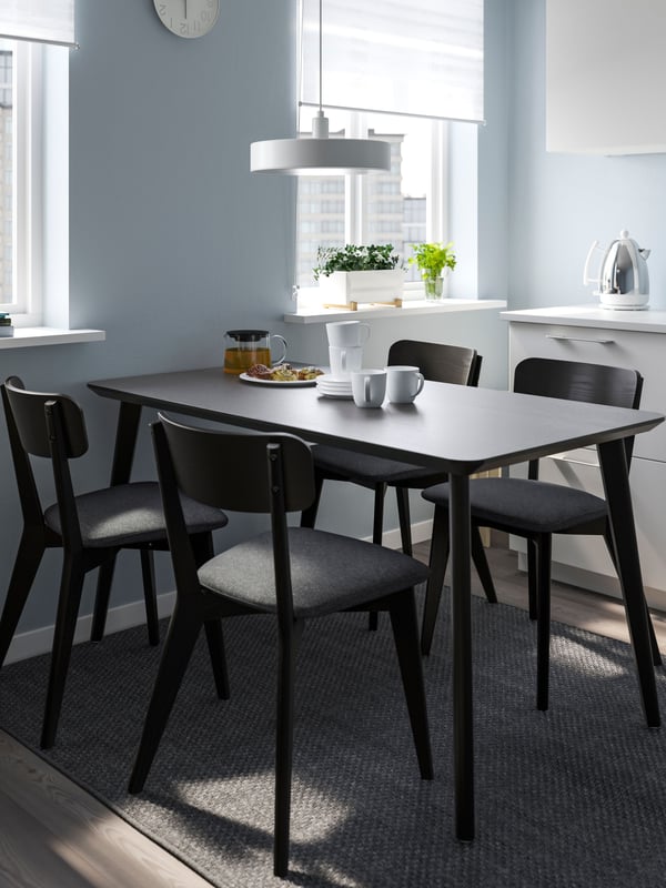 A modern dining room features a black table surrounded by four stylish chairs.