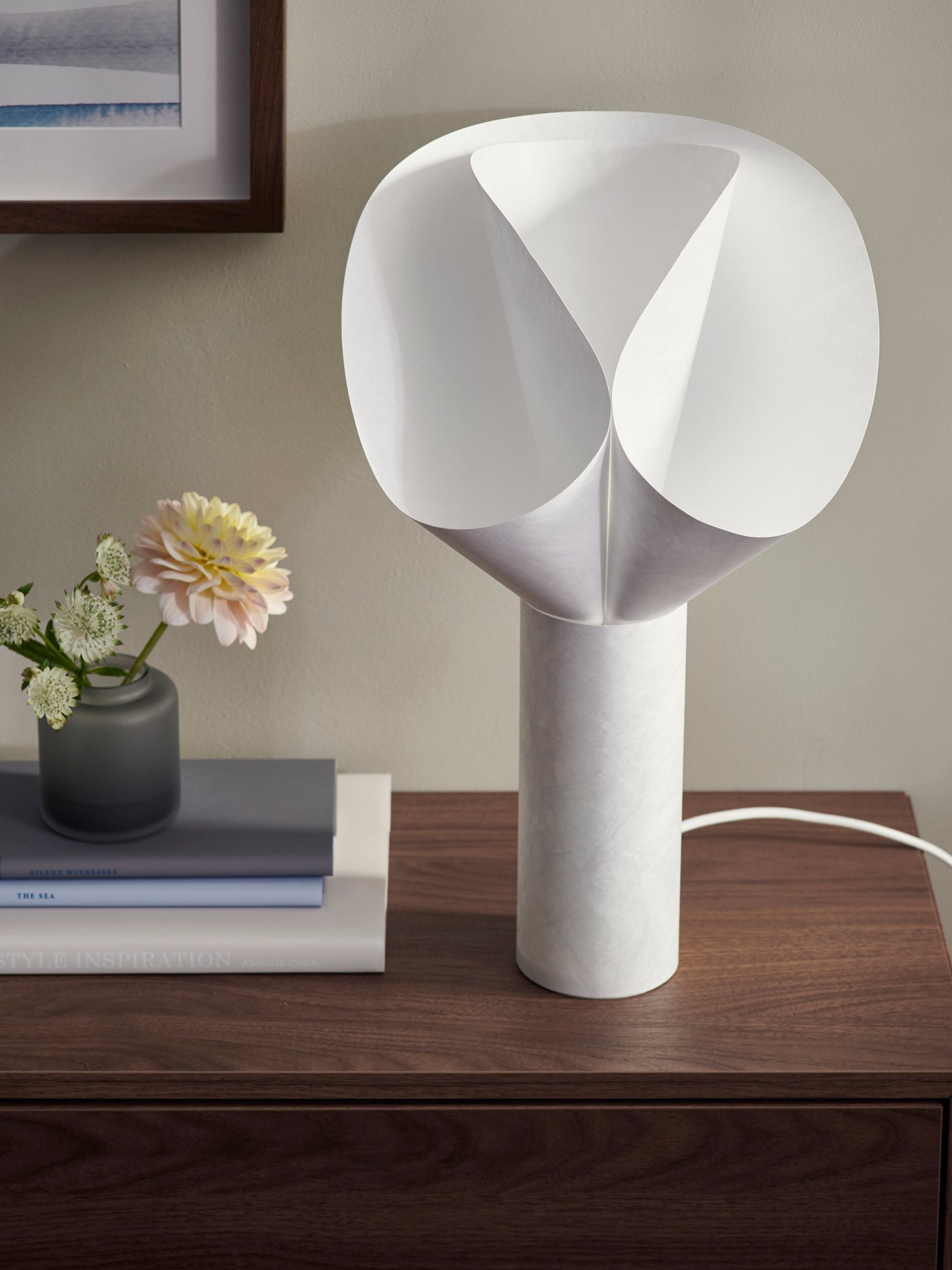 Nærbillede af en hvid BÄCKNATE bordlampe på et mørkebrunt natbord.