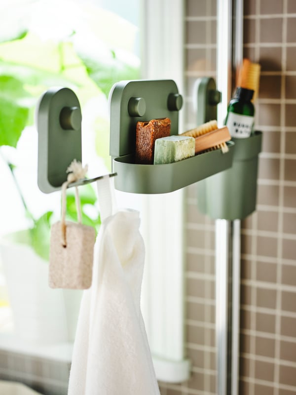 A grey-green ÖBONÄS wall shelf with suction cup