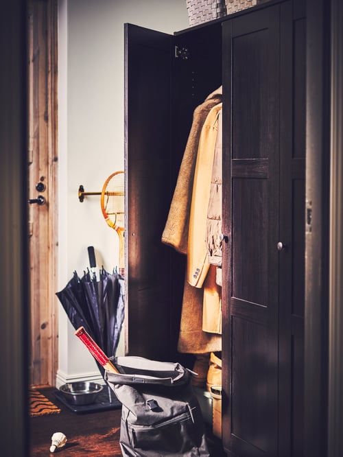 Modern hallway featuring a wardrobe with three doors, one of which is open, a backpack, and an umbrella.