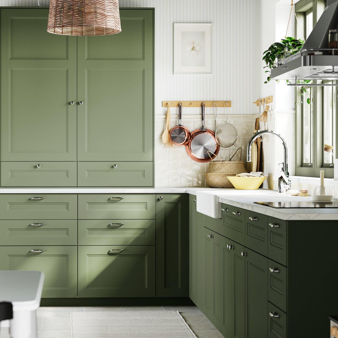 Une cuisine avec des façades gris-vert AXSTAD, éclairée par la lumière naturelle, complétée par des carreaux blancs et des accents en bois.