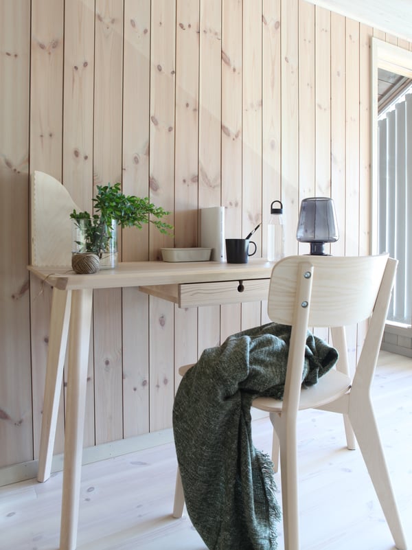 Et LISABO skrivebord og LISABO stol står foran en lys træbeklædt væg i et sommerhus.