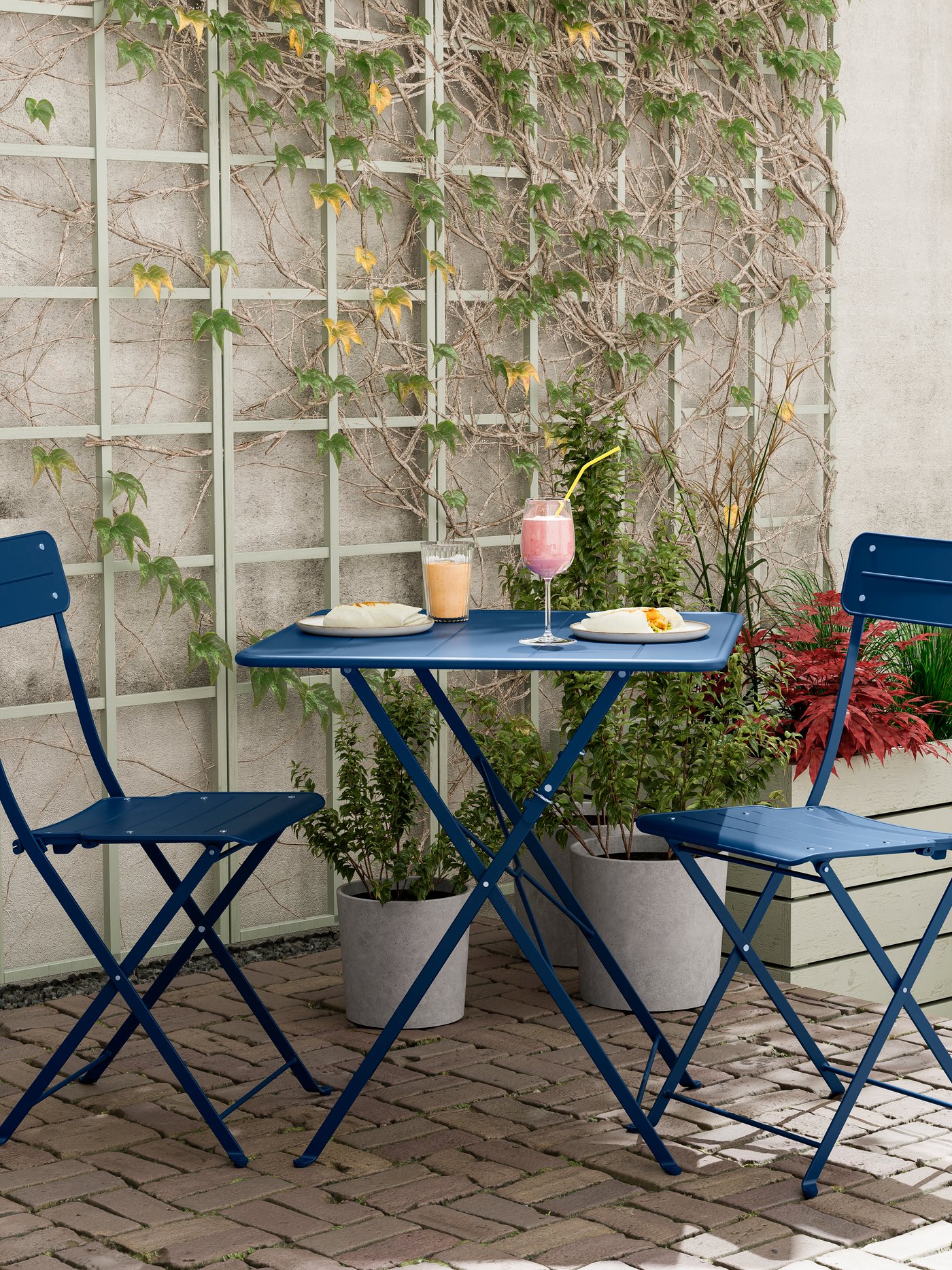 An outdoor dark blue/dark blue SUNDSÖ table and 2 folding chairs outside