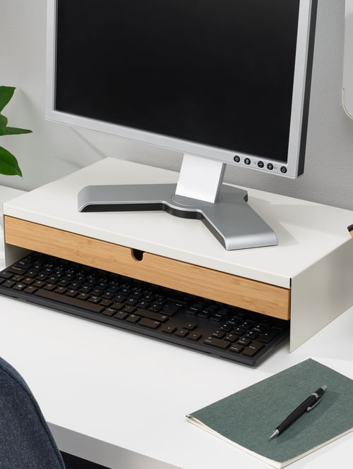 Spațiu de lucru modern în prim-plan pentru un suport pentru monitor de culoare bej, fabricat din oțel, cu sertar din bambus și placă de fibre.