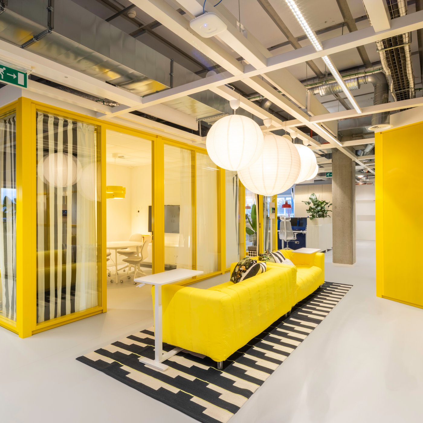 Un coin réunion et lounge jaune vif avec du mobilier IKEA et des accents marquants crée un endroit vivant et stimulant, conçu pour de courtes rencontres et des conversations informelles.