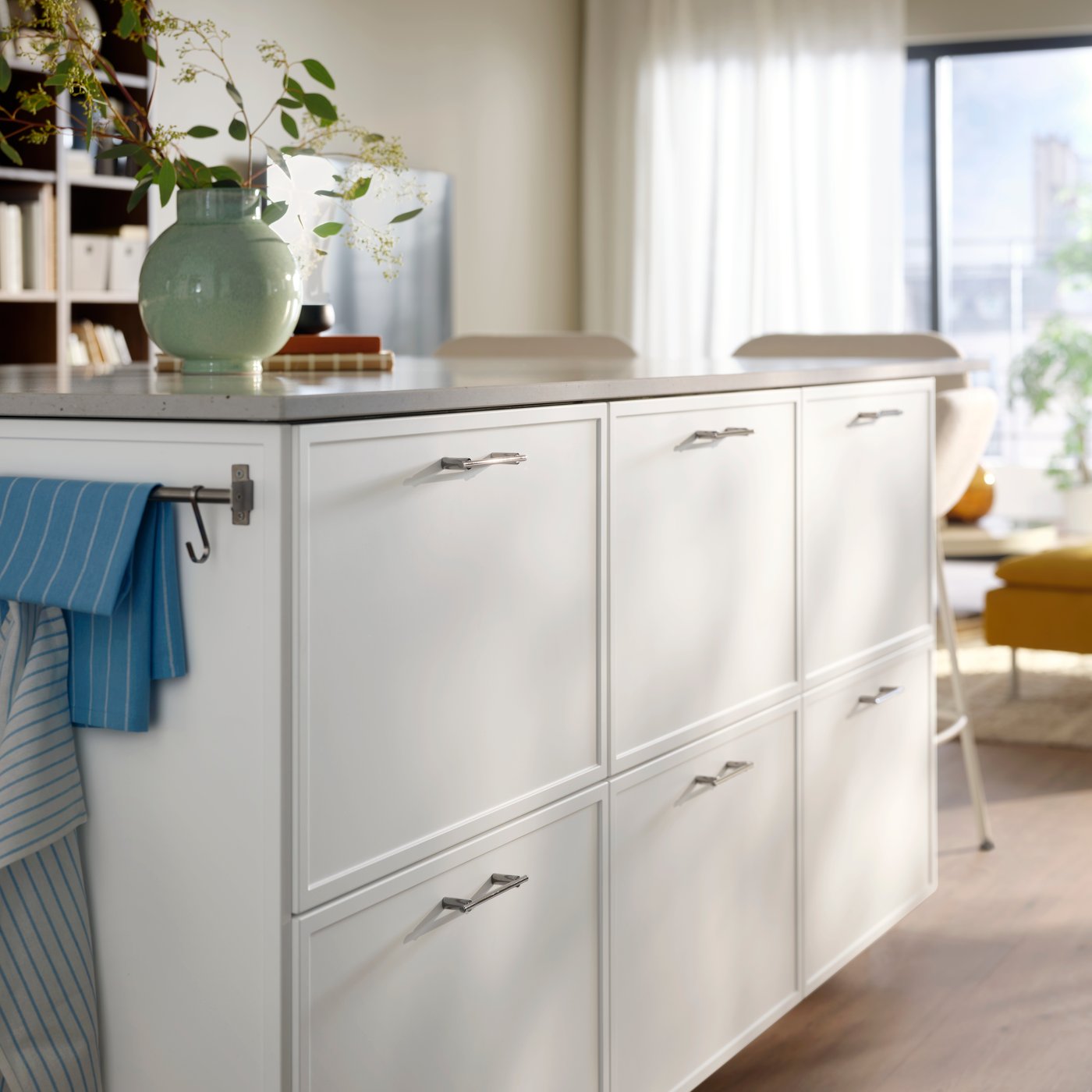 A close-up of a kitchen island with white ASPUDDEN drawer fronts featuring decorative flowers on the countertop.