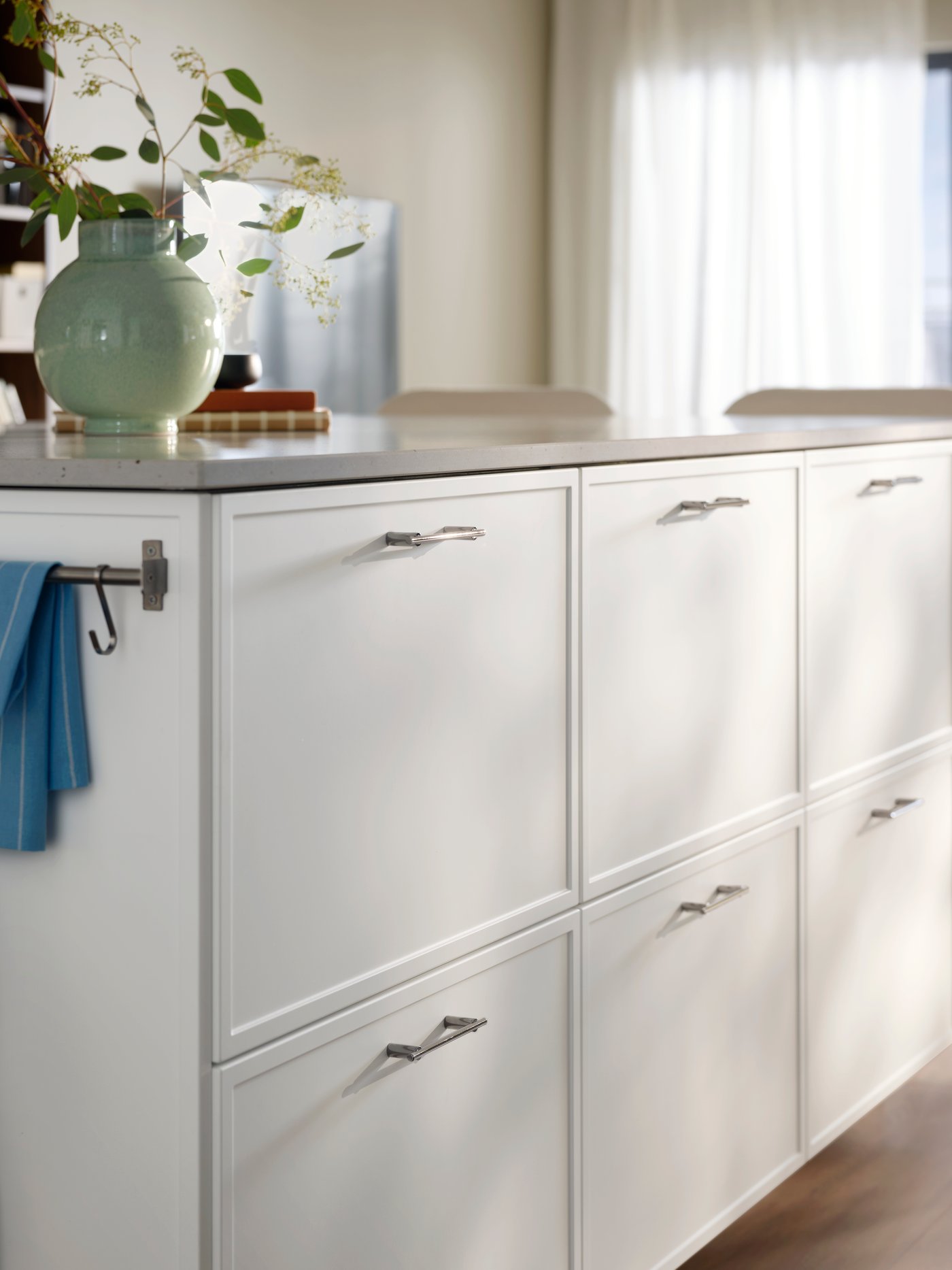 A close-up of a kitchen island with white ASPUDDEN drawer fronts featuring decorative flowers on the countertop.