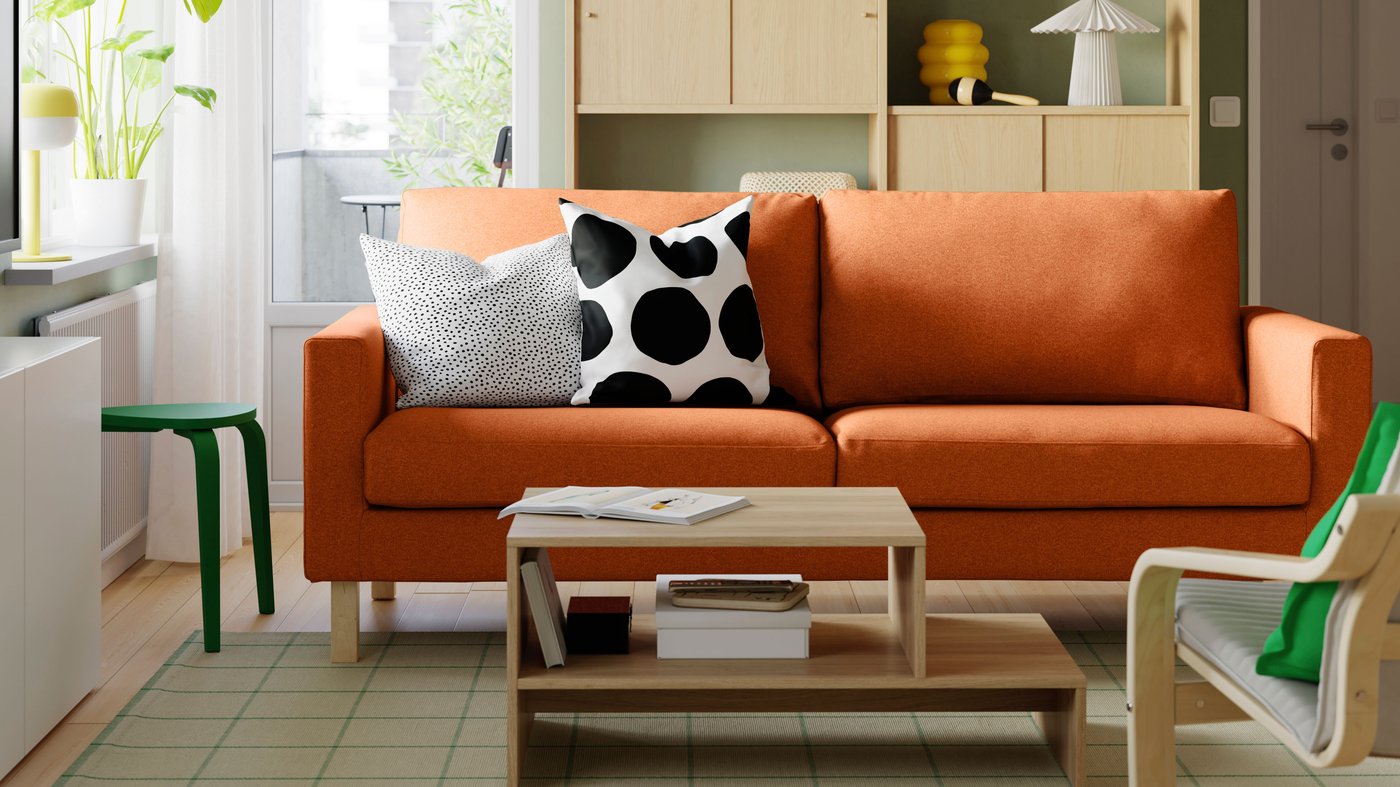 Un sofà SALTSJÖBADEN taronja amb 2 prestatges/combinació d'emmagatzematge LÅDMAKARE d'efecte roure amb portes corredisses
