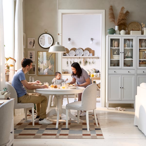 A dining area has a white ROSENTORP extendable table and two chairs, with a view of a kitchen area in the background.