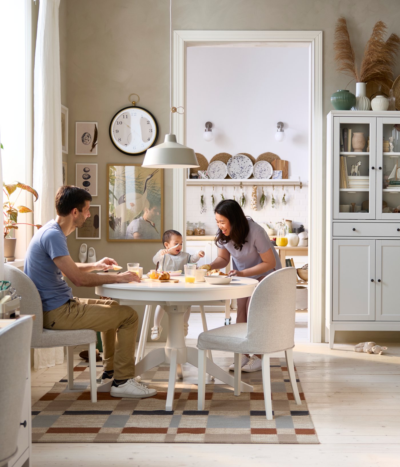 A dining area has a white ROSENTORP extendable table and two chairs, with a view of a kitchen area in the background.