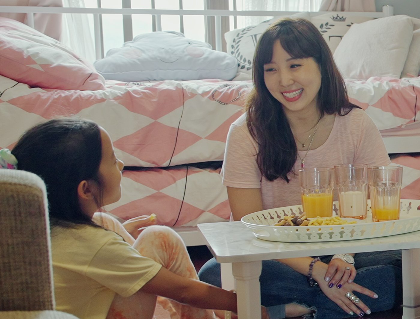 A mother and child enjoy a snack together, sitting at a low table on the bedroom floor.