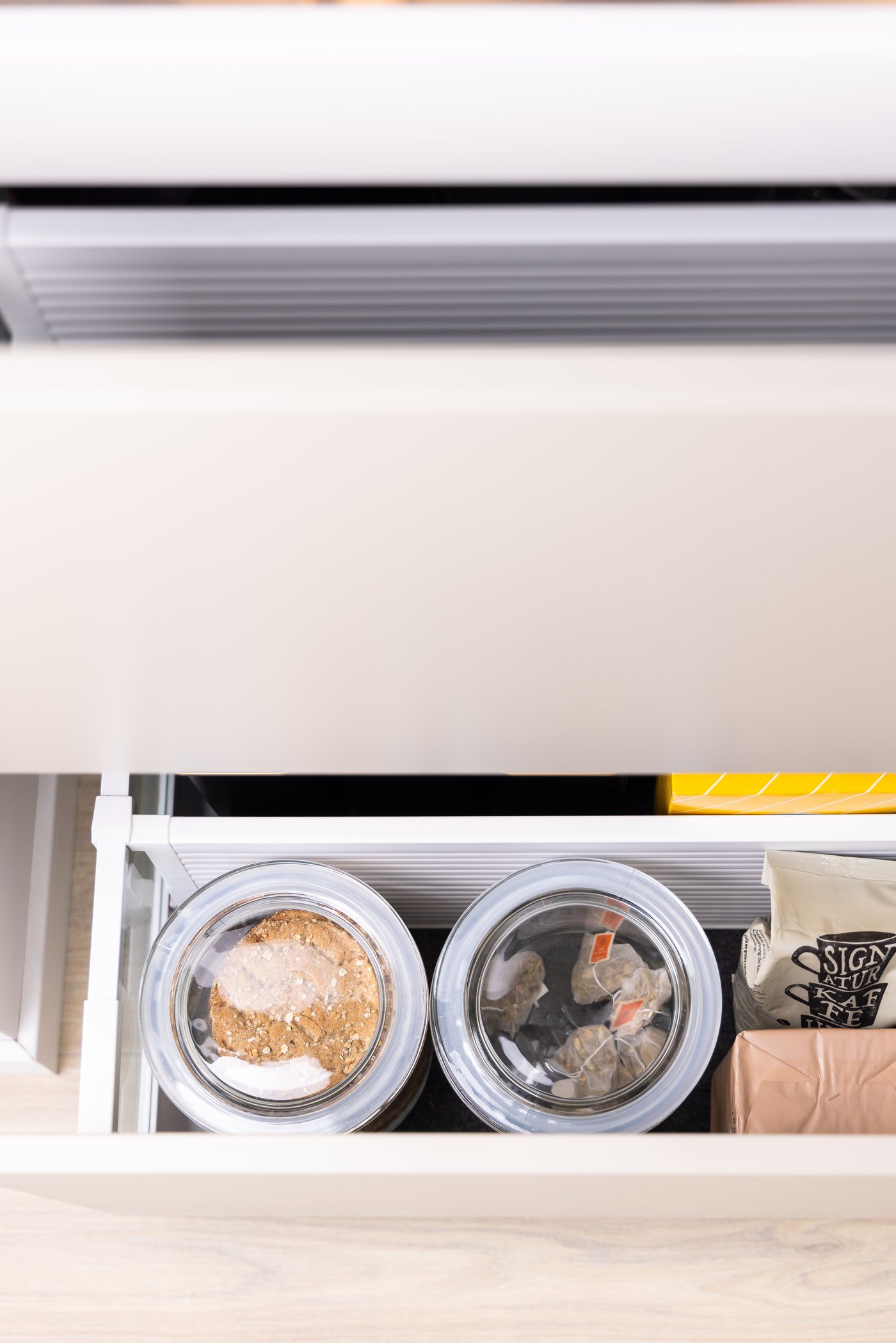 Un cajón con un separador UPPDATERA que separa frascos de vidrio de otras artículos de cocina.