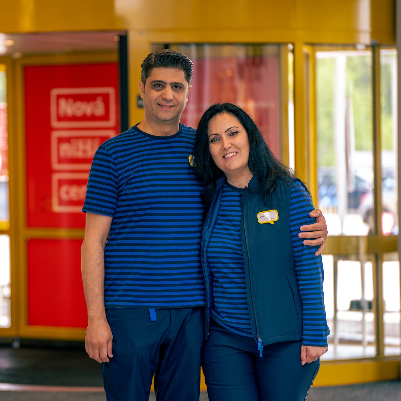 Silva and Abdul in their blue IKEA work uniforms holding each other.