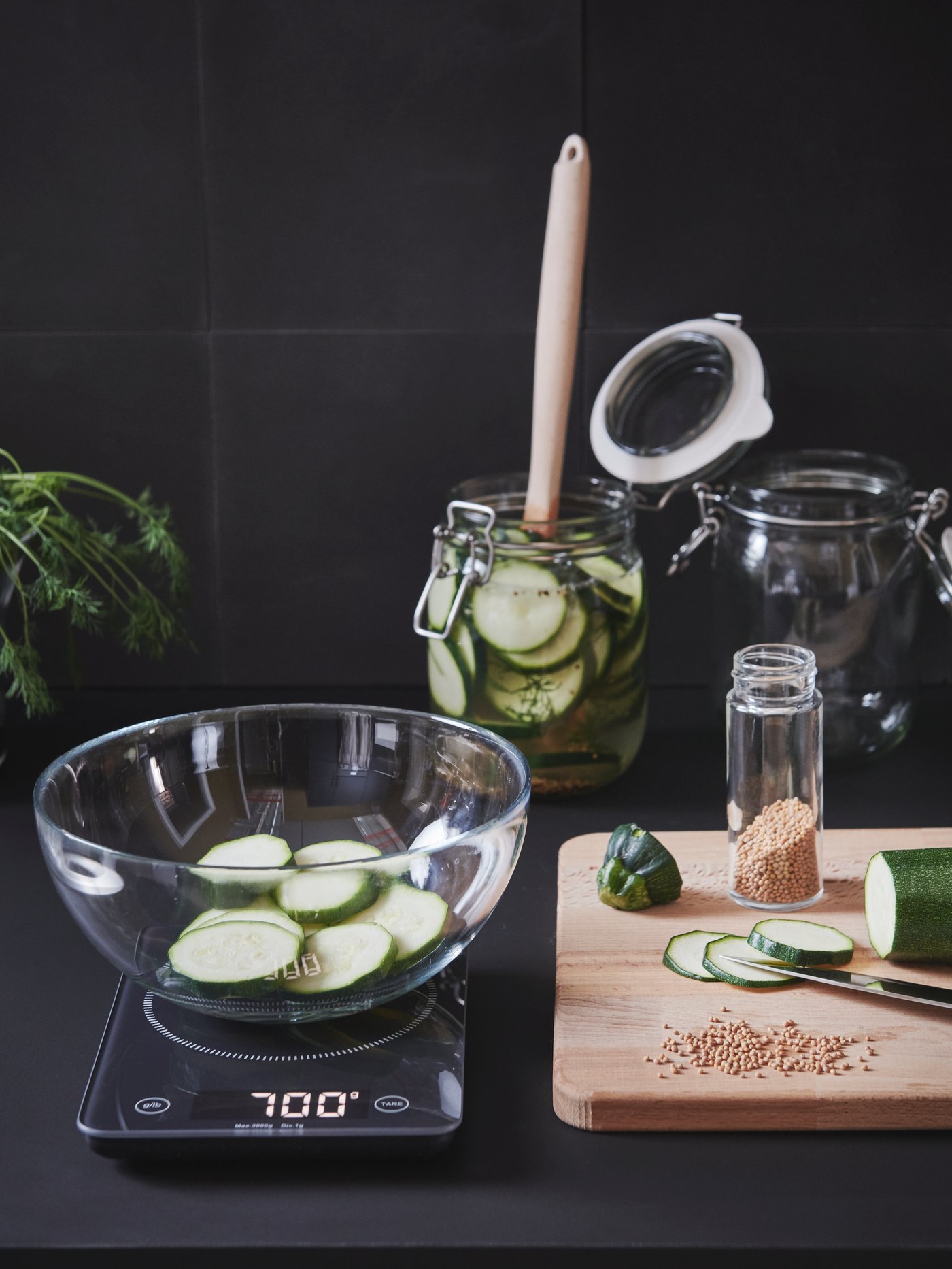 Una báscula negra de vidrio templado con un cuenco para servir blanco junto a una tabla de cortar en una cocina moderna.