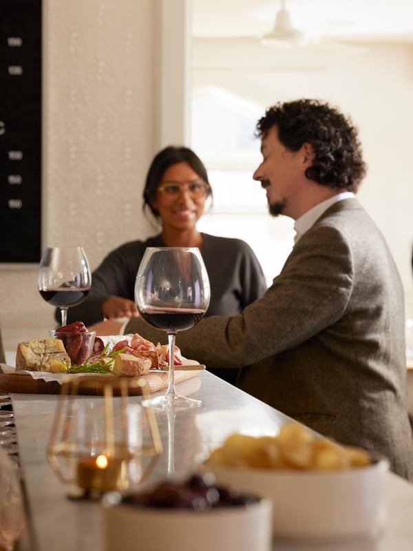 Due persone ad un bancone conversano mentre fanno un aperitivo con bicchieri da vino STORSINT. 