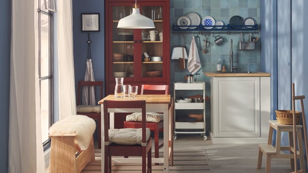 Matplats i svensk allmogestil med vägg i blått kakel, rödlaserade PINNTORP stolar och möbler i traditionell stil.