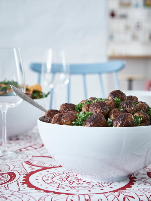 Auf einem gedeckten Tisch ist eine weiße IKEA 365+ Schüssel in gerundeter Form zu sehen, die mit ALLEMANSRÄTTEN Fleischbällchen gefüllt ist.