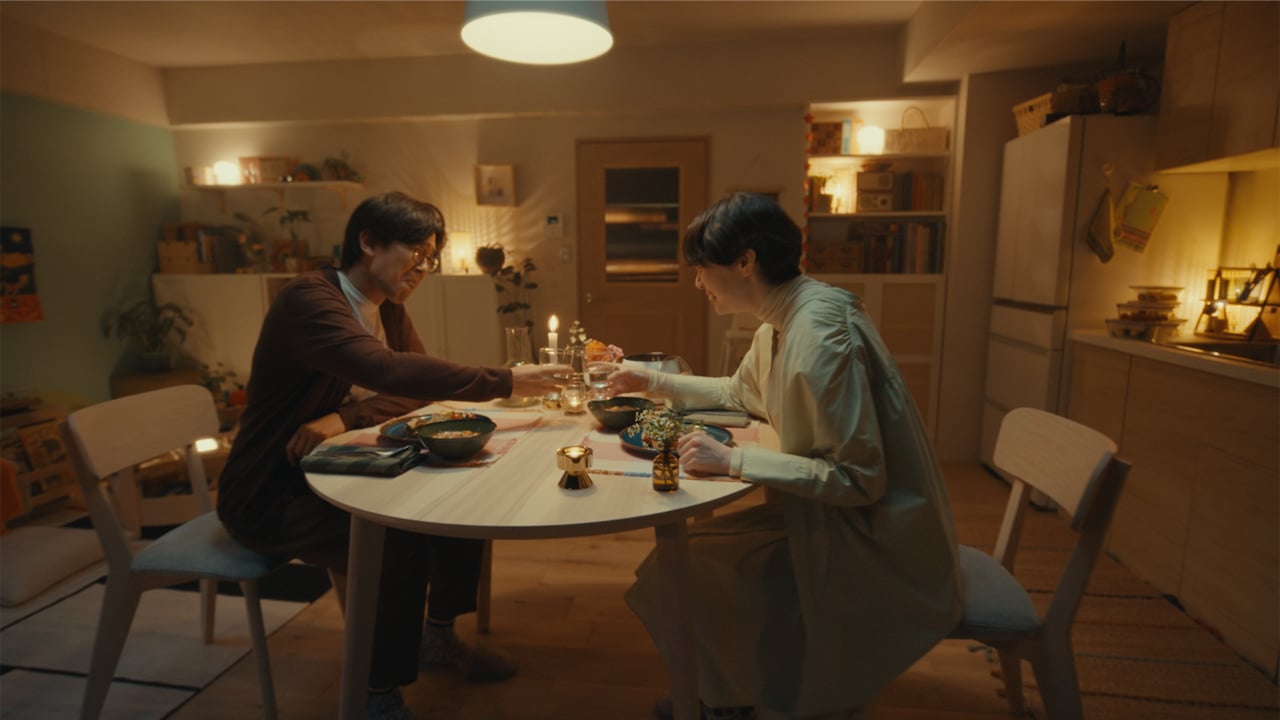 キャンドルが灯る温かなダイニングで、テーブルに並ぶ料理と飲み物を囲む食事シーン
