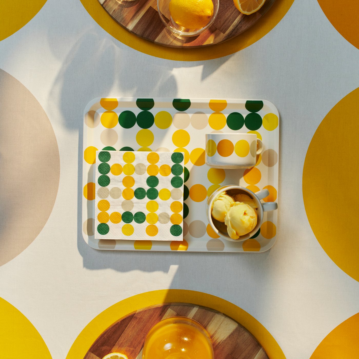 Un vassoio rettangolare bianco BRÖGGAN visto dall'alto che contiene un gelato in coppetta e un tovagliolo di carta a pois. 