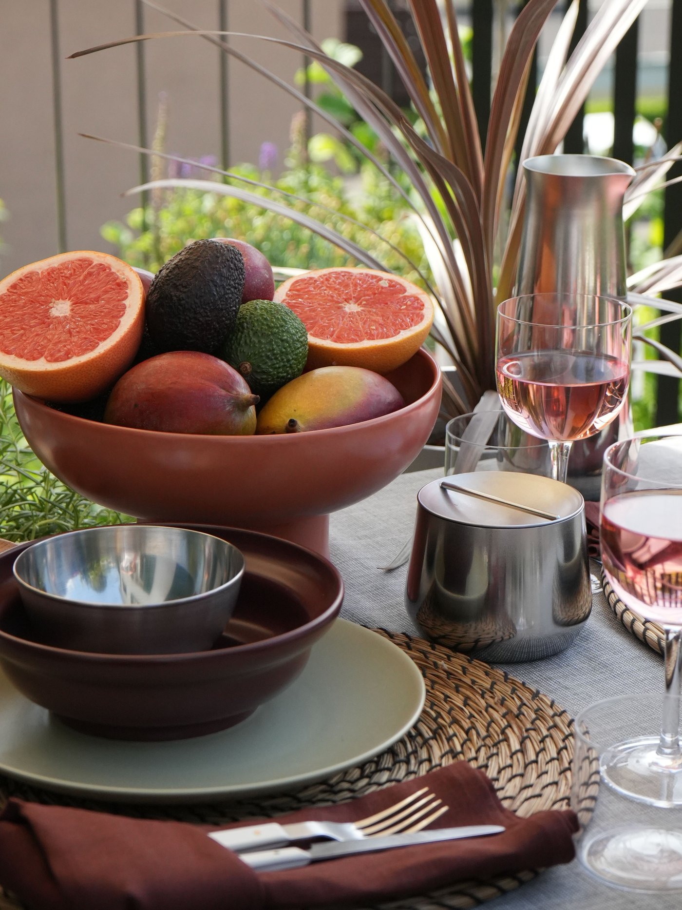 Table dressée en plein air avec des fruits et du vin rosé. Bol en acier inoxydable IKEA BLANDA BLANK, bol marron.