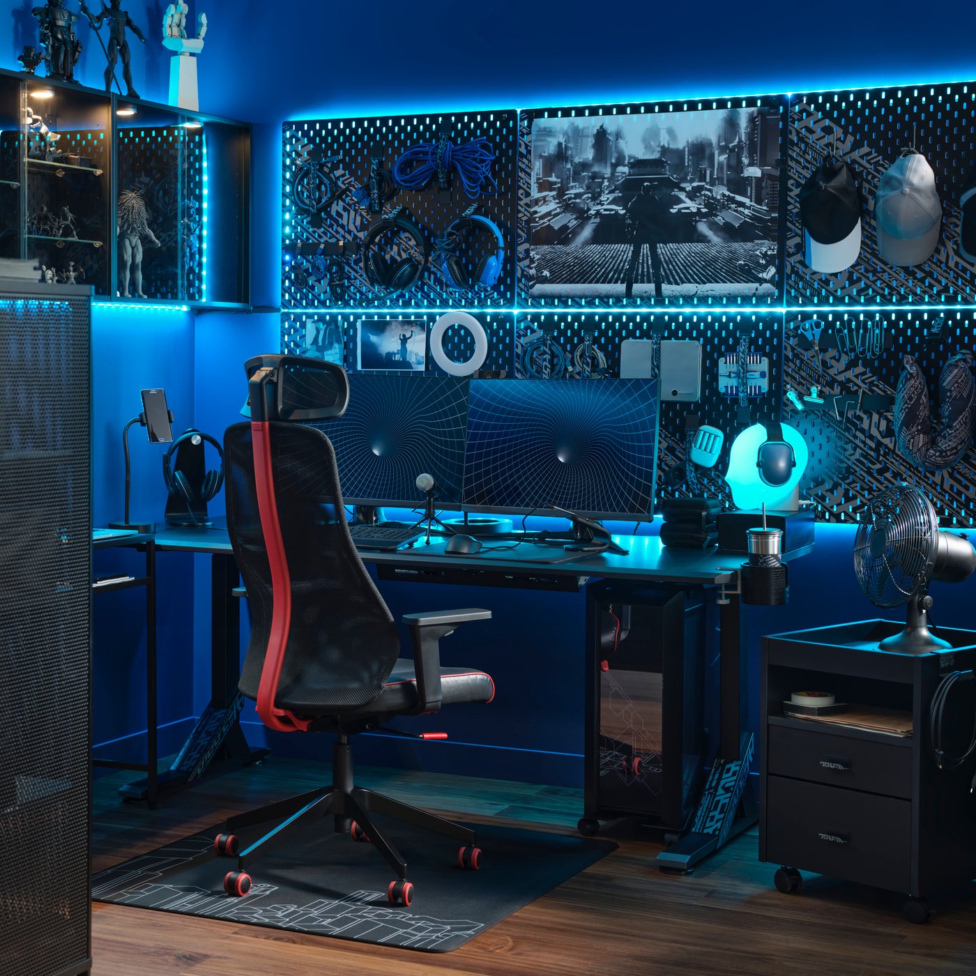 IKEA MATCHSPEL Bomstad black gaming chair in the gaming room lit with blue light, furnished with two monitors, desk, cabinetry, peg boards, and a variety of gaming accessories.