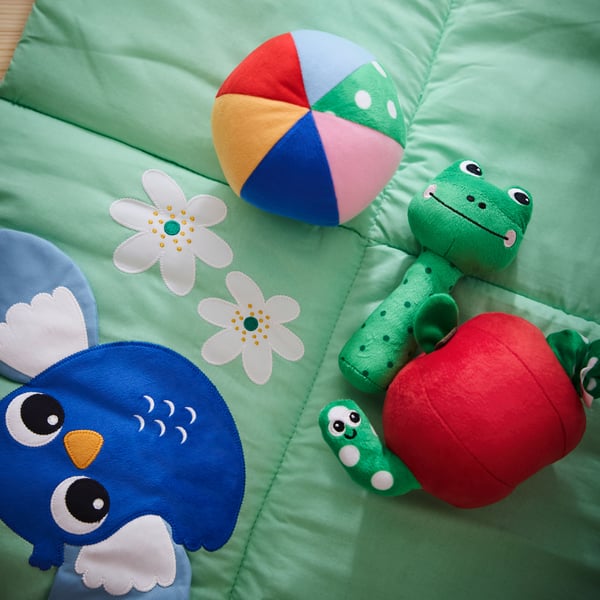 A green SANDBI rattle frog, soft toy and musical toy, lying on top of a SANDBI play mat.