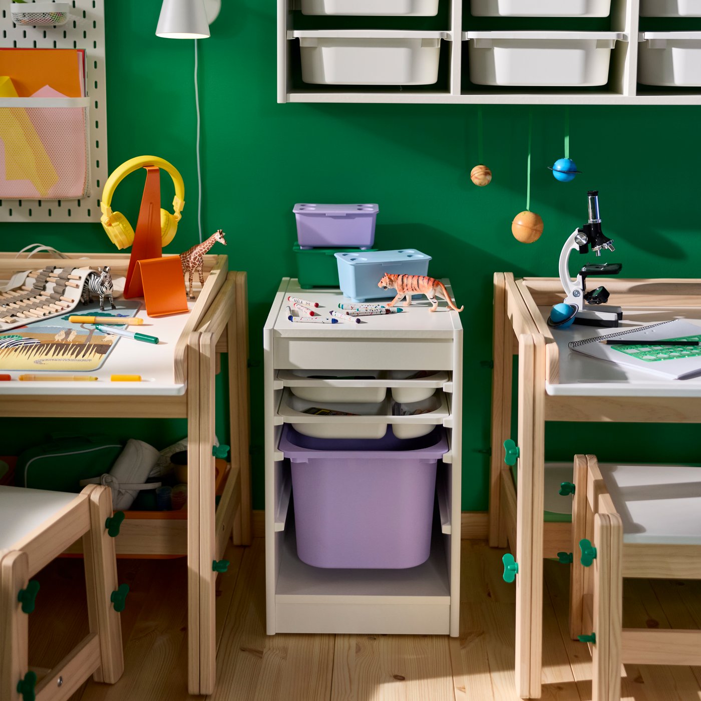 A storage combination from the TROFAST series with box/tray placed beside a children’s desk against a green wall.