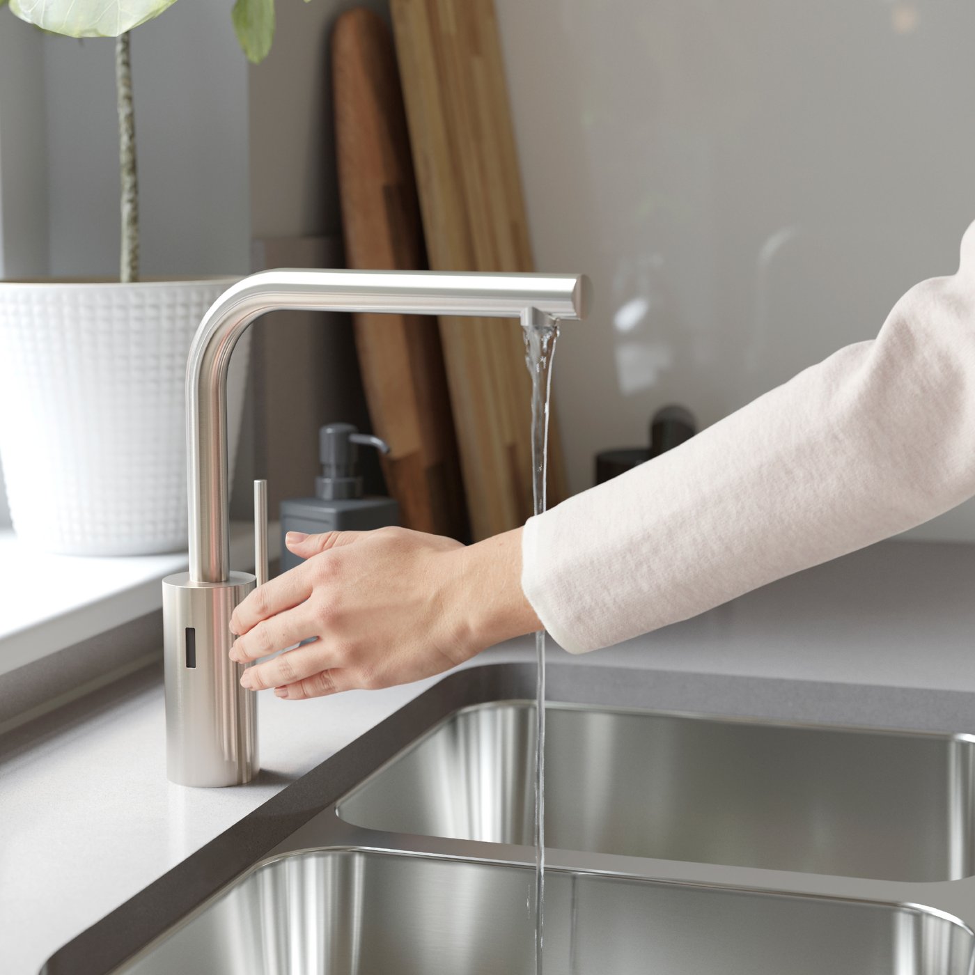 Una mano controlando una llave de lavaplatos TÄMNAREN