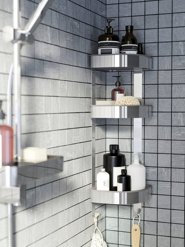 Eine Dusche in Grau mit einem BROGRUND Wandeckregal aus Edelstahl, in dem Duschgel, Shampoo und mehr aufbewahrt werden.