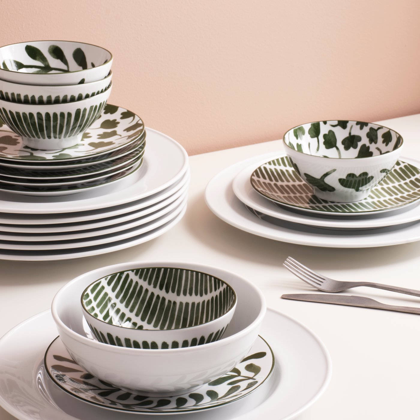 Patterned/green ENTUSIASM bowls and side plates are stacked on a white surface together with white VARDAGEN plates.