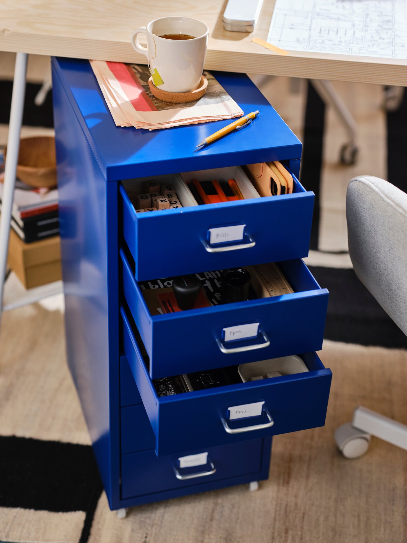 En blå utdragbar lådhurts med skrivbordstillbehör i.