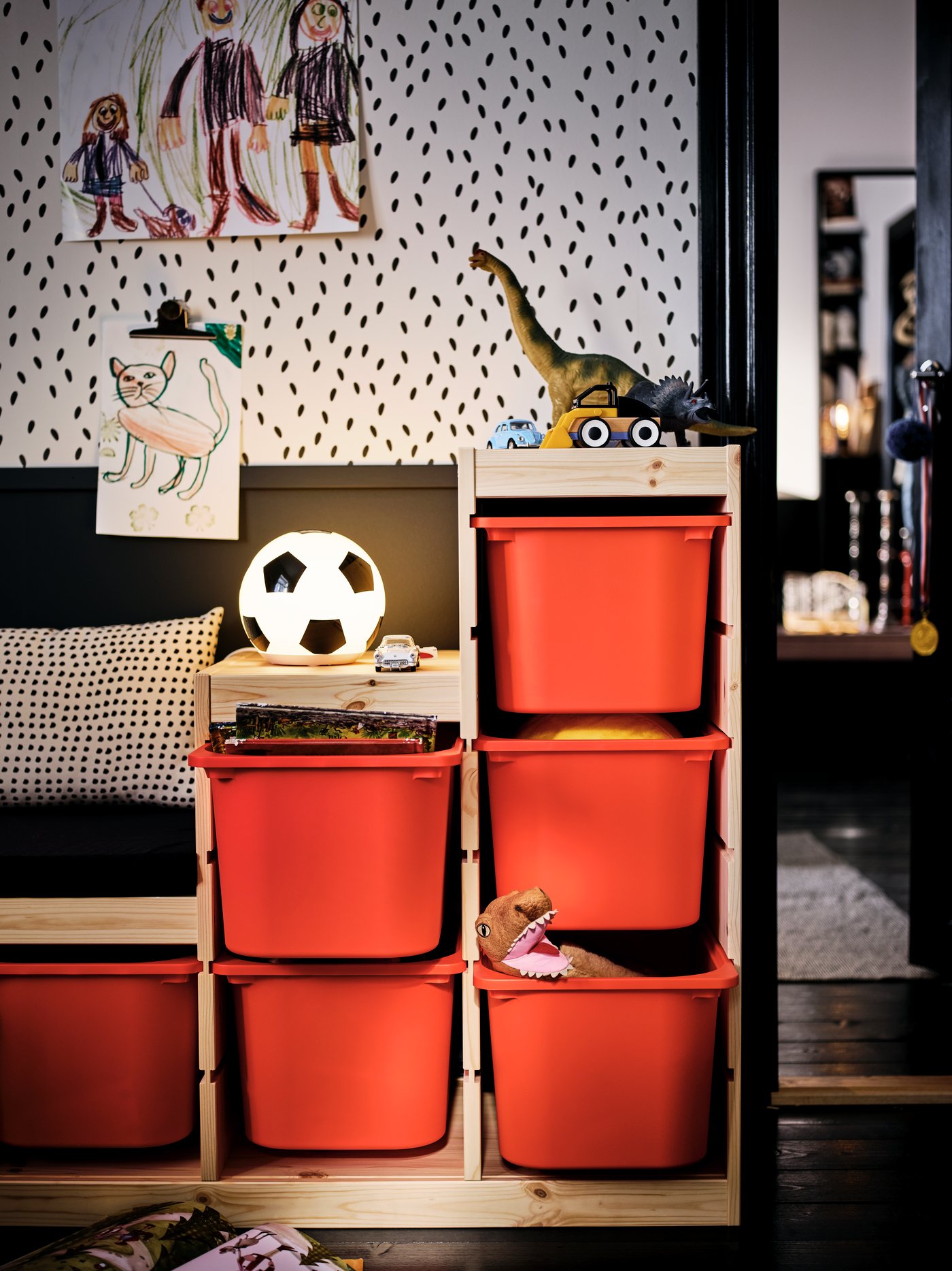 A TROFAST unit with orange storage boxes contrasts against a room set in an entirely black-and-white colour scheme.
