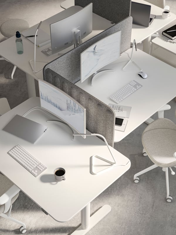 Multiple white desks sitting next to each other with gray privacy boards between them.