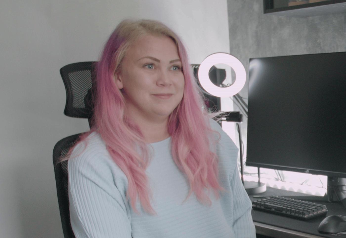 لاعبة ألعاب بشعر وردي تجلس على كرسي.