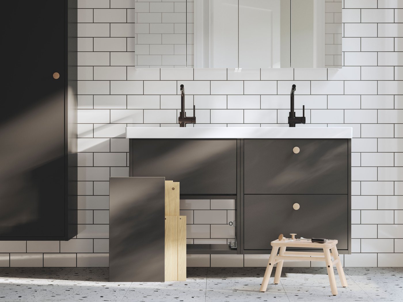 New washstands with washbasins are being installed in a bathroom. There’s part of a drawer on the floor and tools on a stool.