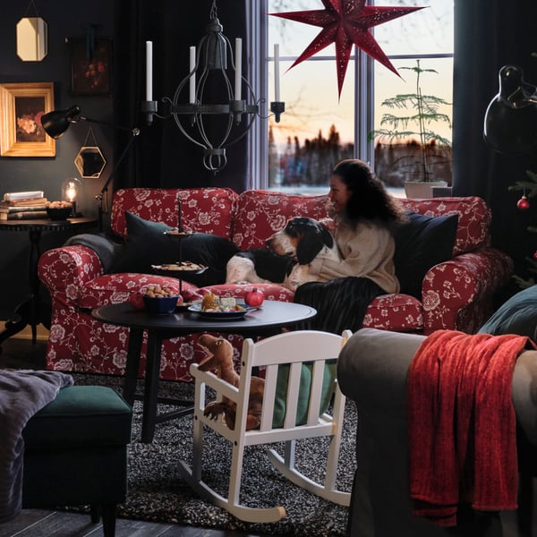 En kvinna kramar en hund  i en julig soffa.