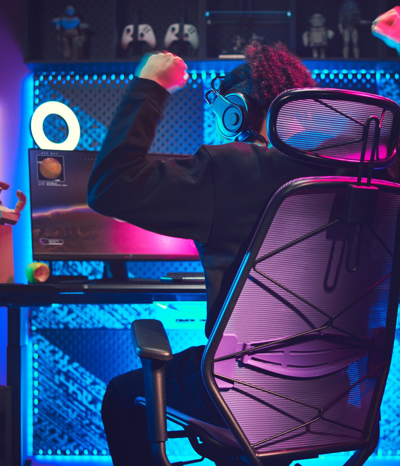 Una stanza da gaming buia con una postazione illuminata. Una persona, seduta su una sedia da gaming, solleva le braccia in segno di vittoria.