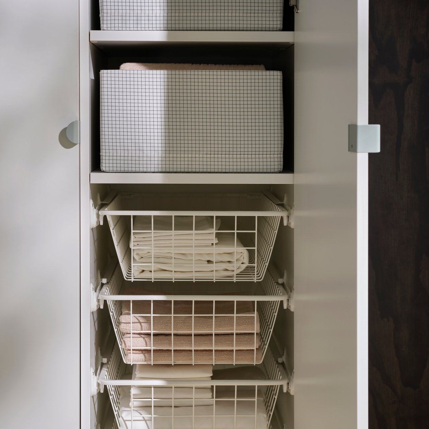 Inuti en LASTARE garderobskombination med STUK lådor på hyllor och trådkorgar som rymmer prydligt vikta textilier.