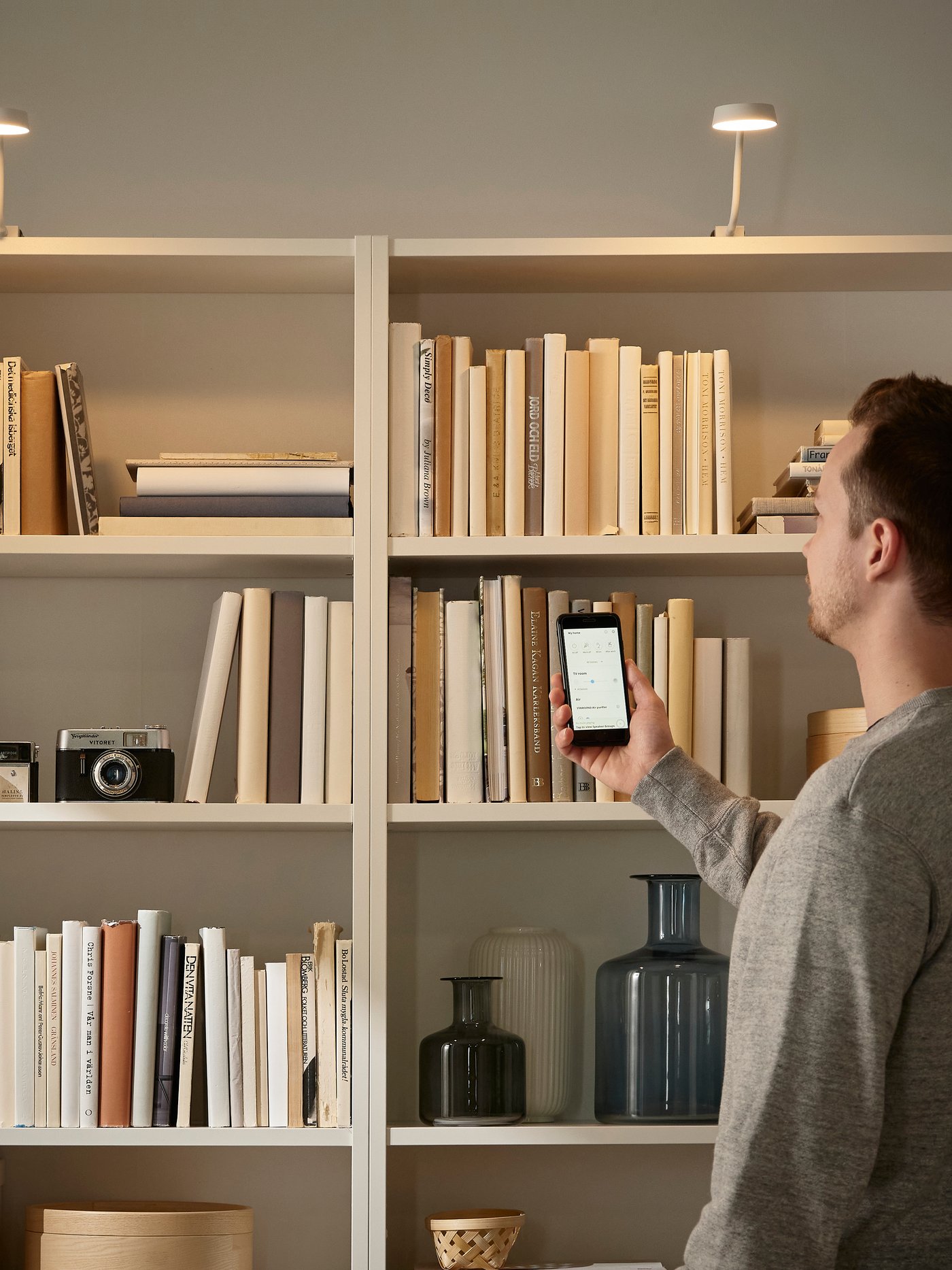 Mężczyzna sterujący oświetleniem regału za pomocą aplikacji.