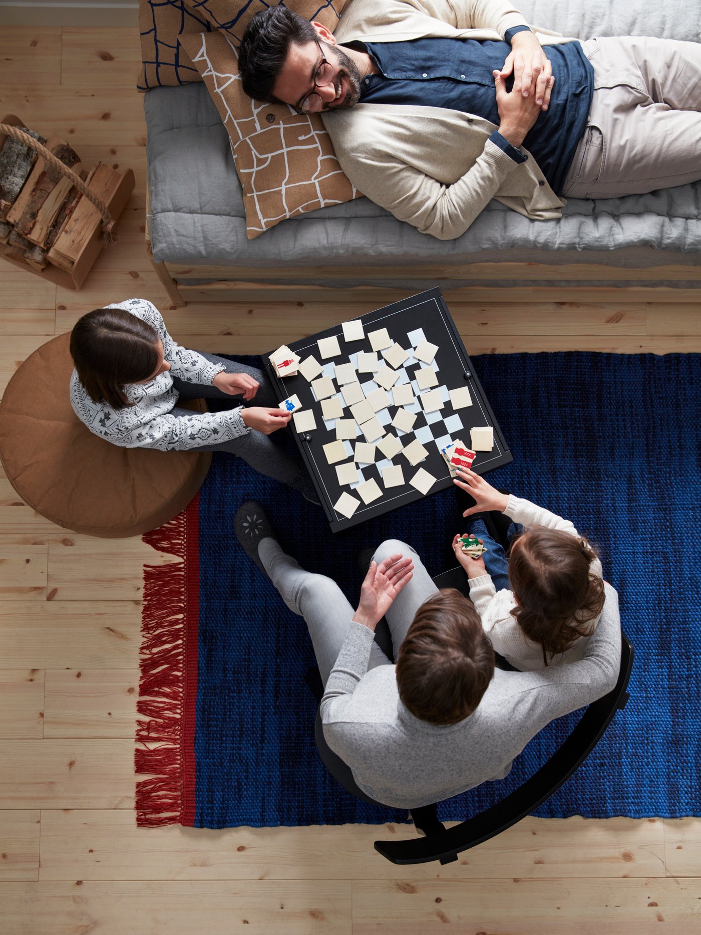 A family is playing a game of memory on New Year’s Eve while the father is lying on the sofa.