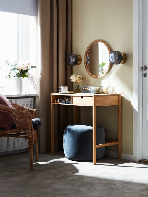 Modernes Schlafzimmer mit einem NORDKISA Frisiertisch, zwei SOLKLINT Wandleuchten, einem runden Spiegel, einem AGEN Stuhl und einer GODMORGON Minikommode mit 2 Schubladen.