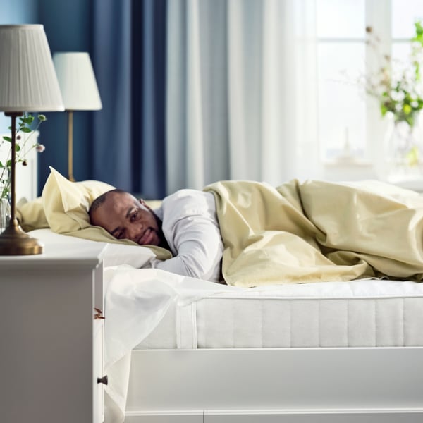 Un hombre recostado sobre una cama doble con un colchón VESTMARKA.