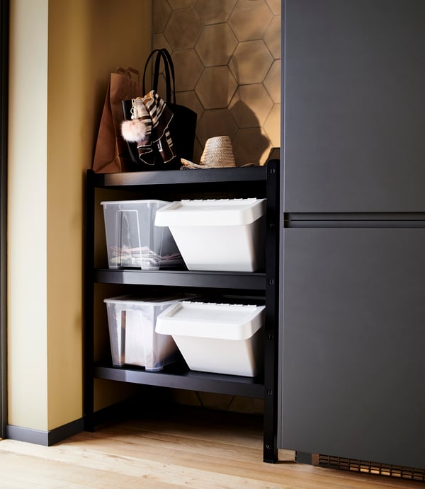 BROR shelving rack with SORTERA bins on shelves next to SAMLA storage boxes and a handbag and hat on top. 