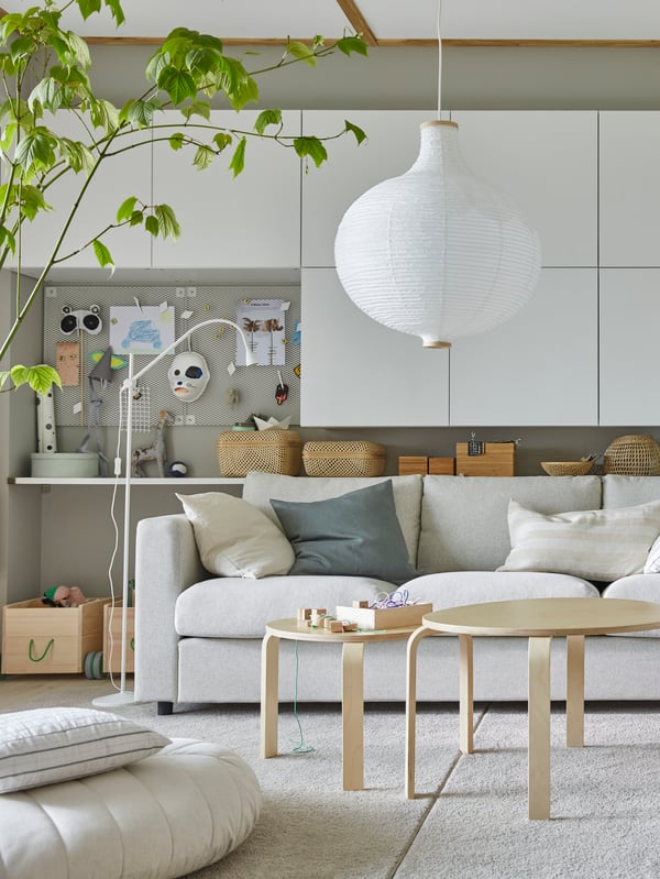 Parte de uma sala com arrumação BESTÅ em branco na parede por trás de um sofá VIMLE em bege e duas mesas de centro em chapa de bétula.